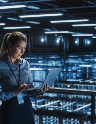 Data Center Female It Specialist Using Laptop. Server Farm Cloud Computing and Cyber Security Maintenance Administrator Working on Computer. Information Technology Professional.