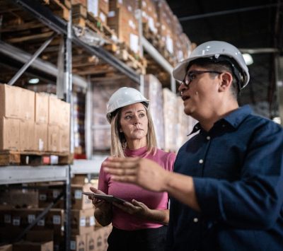 Coworkers talking and using digital tablet in a warehouse